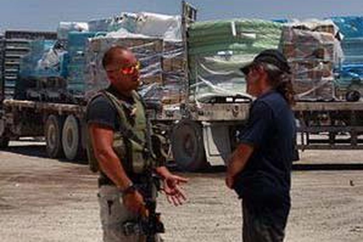 Seorang personel militer Israel berbincang-bincang dengan dengan sopir truk saat pemindahan barang bantuan ke truk Palestina.