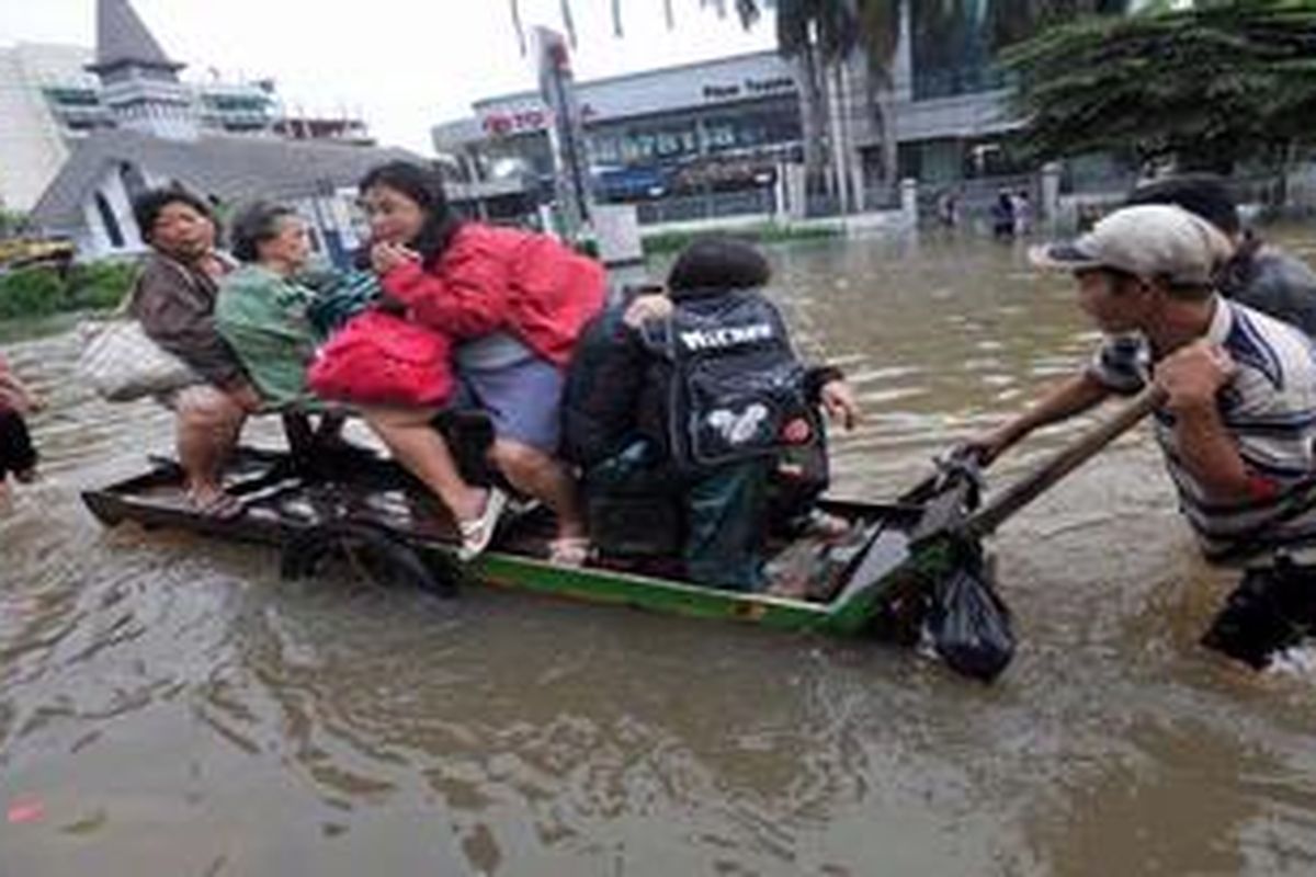 Warga memanfaatkan jasa gerobak untuk angkutan melintasi banjir di Jalan Kyai Tapa, Jakarta Barat, Jumat (18/1/2013). Untuk sekali angkut mereka harus mengeluarkan ongkos antara Rp 20.000-Rp 100.000 tergantung beban dan jarak tempuhnya.