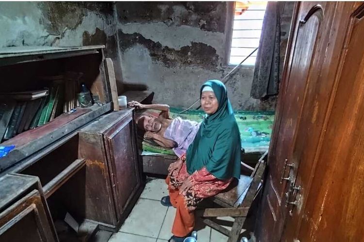Dasini, istri Carli, menunjukan kondisi kesehatan Carli yang sudah terbaring di kasurnya di Desa Benda, Kecamatan Karangampel Kabupaten Indramayu, pada Rabu (9/10/2024) siang. Carli adalah satu dari beberapa pencipta lagu yang bernasib pilu karena tidak mendapatkan royalti hingga usia renta.