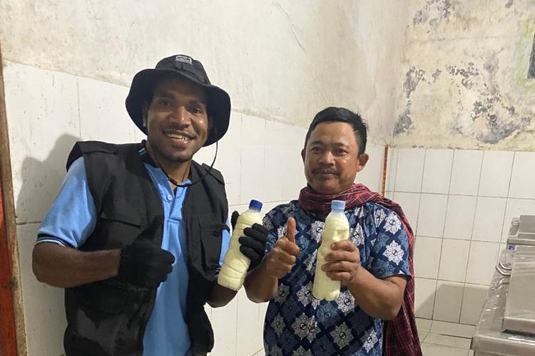 Mahasiswa Universitas Negeri Malang asal Papua, Agodonas Kasipmabin (21) bersama salah satu warga yang merupakan peternak sapi perah, saat memegang hasil produksi Susu Botoputih (Subot) di Kampung Botoputih, Kabupaten Trenggalek, Provinsi Jawa Timur pada bulan Oktober 2022.
