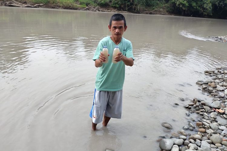 Seorang warga di DAS Malinau menunjukkan kondisi air setelah kolam penampungan limbah PT KPUC jebol 7 Februari 2021 lalu
