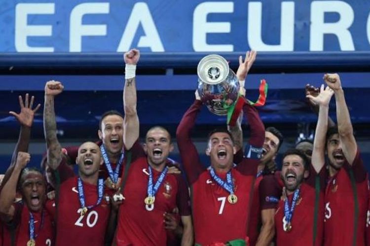 Penyerang Portugal Cristiano Ronaldo (tengah) mengangkat trofi saat merayakan kemenangan bersama timnya yang memenangi final Piala Eropa Euro 2016, Senin (11/7/2016). Portuga mengalahkan Perancis 1-0 saat final di Stade de France.