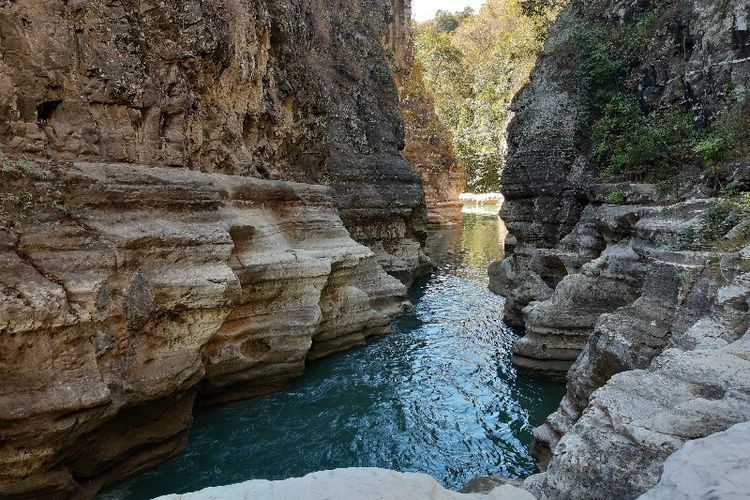 Tampak dinding batu yang menjulang tinggi mengapiti sungai di tempat wisata Tanggedu.
