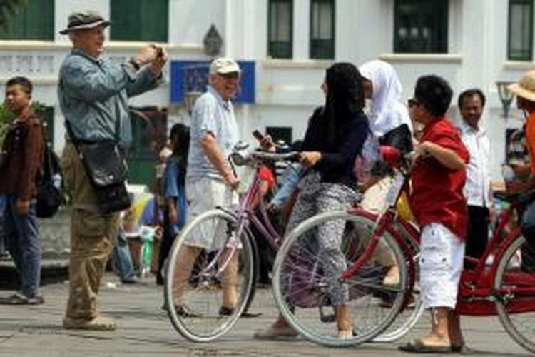 Wisatawan mancanegara memotret wisatawan lokal yang sedang mengendarai sepeda sewaan di lapangan Taman Fatahillah di kawasan Kota Tua Jakarta Barat, Rabu (30/7/2014). Dua hari setelah lebaran, kawasan Kota Tua dipenuhi warga yang mengisi masa liburan bersama keluarga.