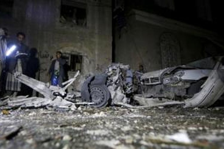 Aparat keamanan Yaman memeriksa bangkai mobil yang hancur akibat bom di ibu kota Yaman, Sana'a, yang menewaskan sedikitnya 28 orang.