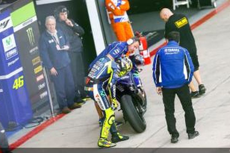 Pebalap Movistar Yamaha Valentino Rossi memperhatikan ban belakang motornya setelah menjalani sesi latihan bebas kedua GP Argentina di Sirkuit Termas de Rio Hondo, Jumat (25/4/2014).