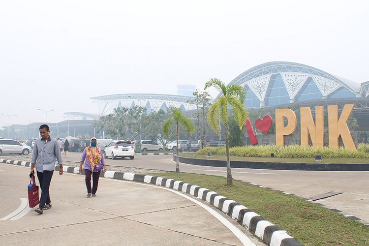 Warga berjalan di kompleks Bandara Supadio yang diselimuti kabut asap di Kabupaten Kubu Raya, Kalimantan Barat, Minggu (15/9/2019). Plt Kadiv Operasional Bandara Internasional Supadio Pontianak Andry Felanie menyatakan bahwa pada Minggu (15/9/2019) terdapat 19 penerbangan keberangkatan dan 18 penerbangan kedatangan yang dibatalkan karena jarak pandang di landasan Bandara Supadio mengalami penurunan akibat kabut asap yang menyelimuti wilayah setempat.