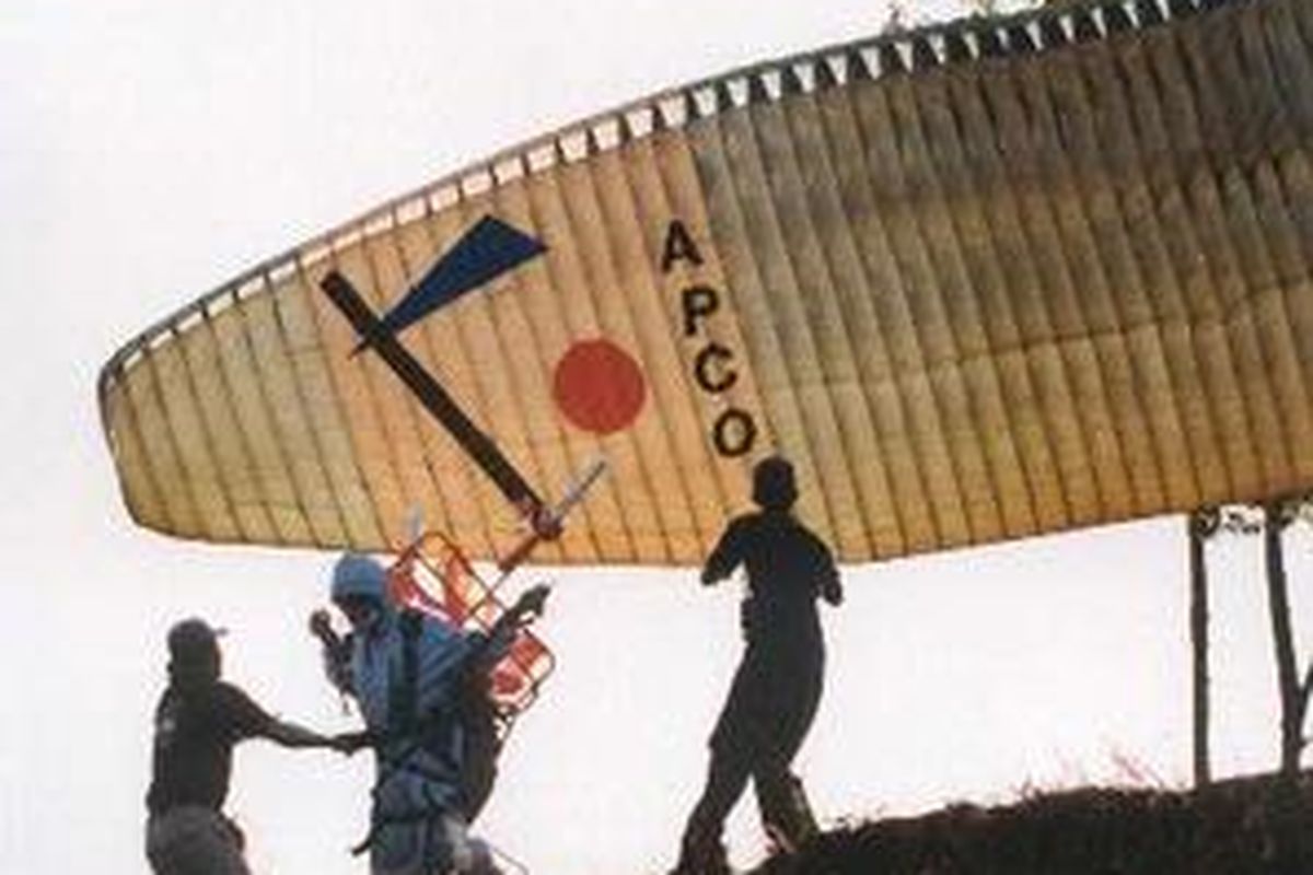 Seorang penggemar olahraga paralayang sedang berusaha terbang dari Gunung Banyak Pujon, Batu. Penggemar paralayang dapat menikmati keindahan Kota Batu saat melayang dari ketinggian lebih dari 1.000 meter di atas permukaan laut.