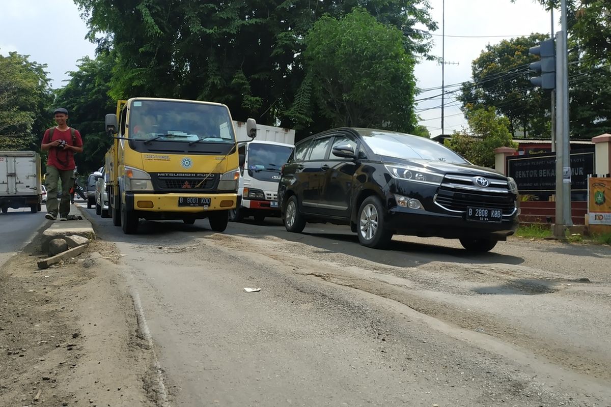 Jalan Raya Siliwangi, Rawalumbu, Kota Bekasi melesak dan bergelombang, menimbulkan perbedaan ketinggian aspal yang rentan mencelakai pemotor di antara truk-truk bertonase besar yang rutin melintas di sana.