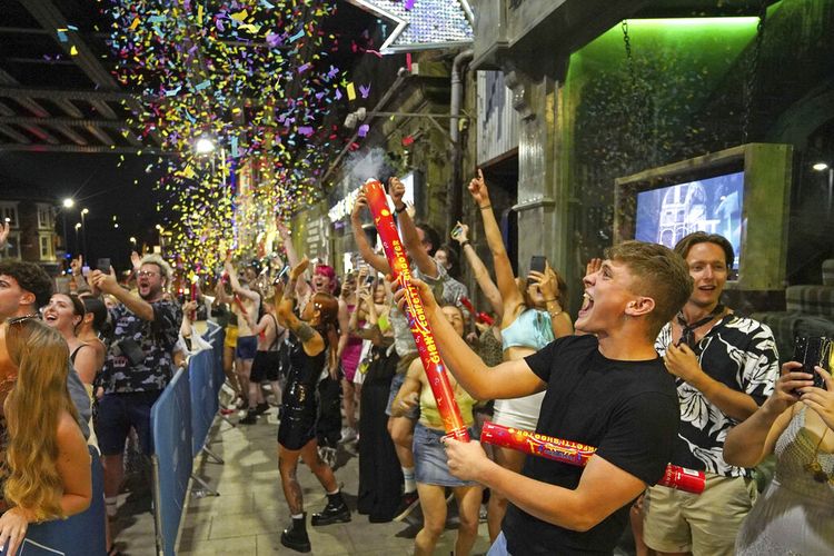 Orang-orang merayakan Hari Kebebasan saat mereka mengantri untuk masuk di Viaduct Bar di Leeds, setelah pembatasan hukum virus corona dicabut di Inggris pada tengah malam, Senin, 19 Juli 2021. 