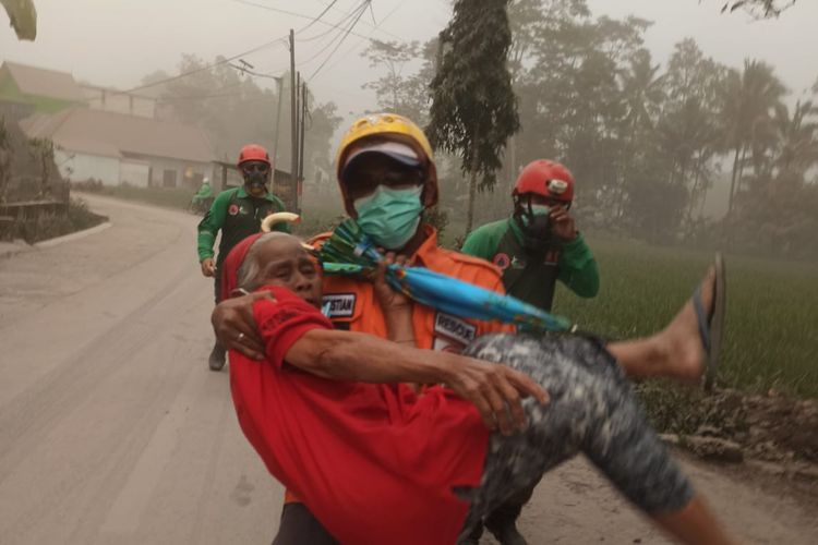 
Seorang petugas terlihat tengah mengevakuasi warga saat erupsi Gunung Semeru, Minggu (4/12/2022).