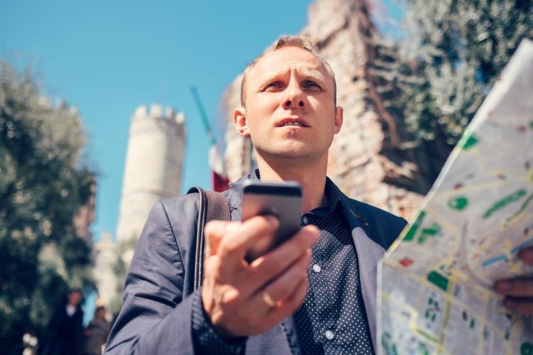 Ilustrasi turis mancanegara memegang ponsel dan peta.