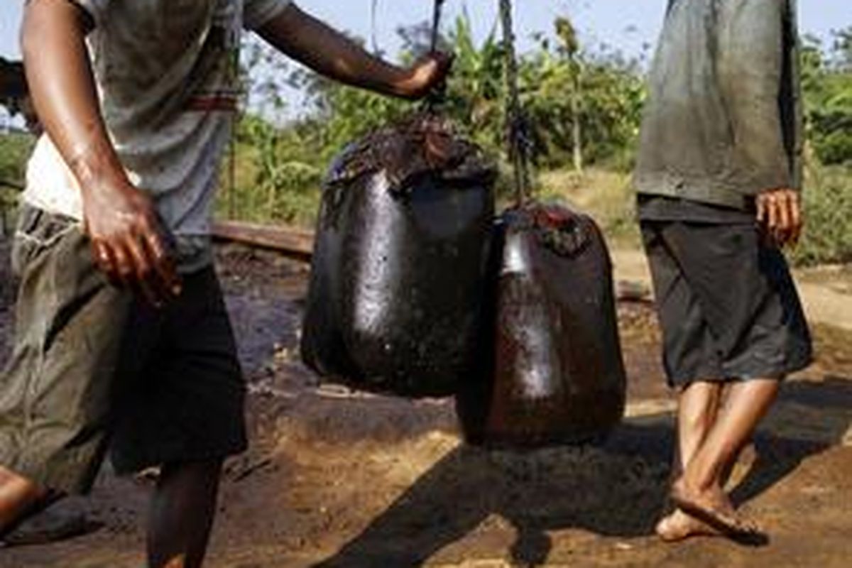 A worker carries containers of crude oil to be processed into fuel at a traditional well in Bojonegoro in Indonesias East Java province July 16, 2009. Few things seem to happen at speed in this sleepy Java town where rickshaws ply the streets. But this rural area of rice fields and teak forests is set to be transformed by Indonesias biggest oil find in years. Picture taken July 16.