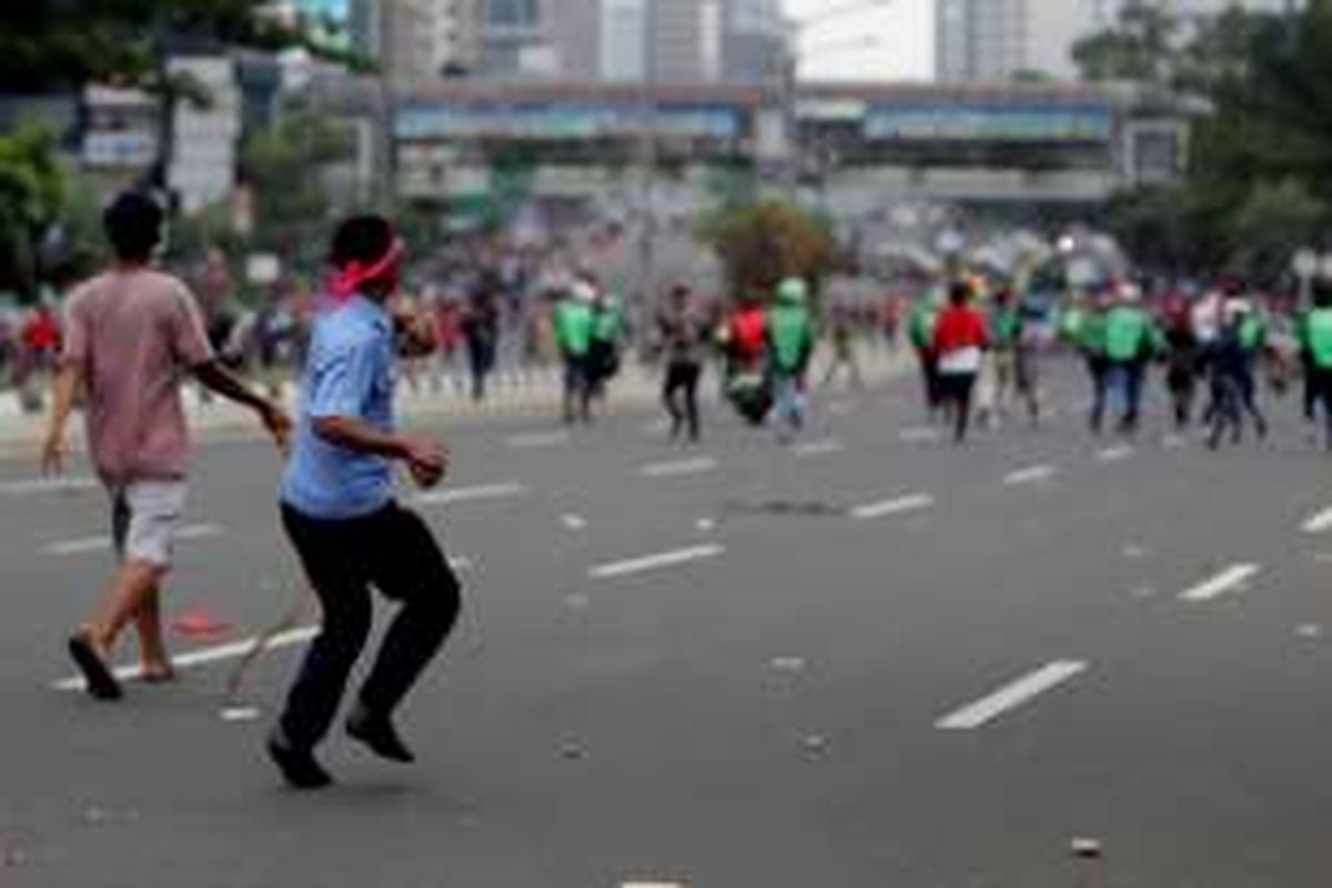 Sejumlah pengemudi ojek online terlibat aksi saling lempar batu dengan para sopir taksi yang berdemonstrasi di Jalan Sudirman, Jakarta, Selasa (22/3/2016). Aksi ini dipicu karena salah satu pengemudi ojek online disweeping oleh para demonstran.