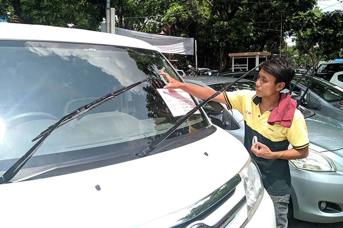 Seorang pedagang memasang kertas berisi spesifikasi mobil yang akan dijual di bursa mobil Sriwedari, Solo, Jawa Tengah, Minggu (15/12/2019). Setiap Minggu ratusan mobil bekas dijajakan di Bursa Mobil Sriwedari.