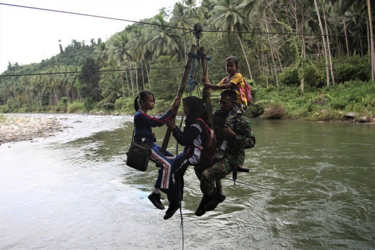 Sersan Kepala (Serka) Darwis dalam aksi heroiknya membantu para pelajar menyerberangi sungai di Desa Maroko, Kolaka, Sulawesi Tenggara.