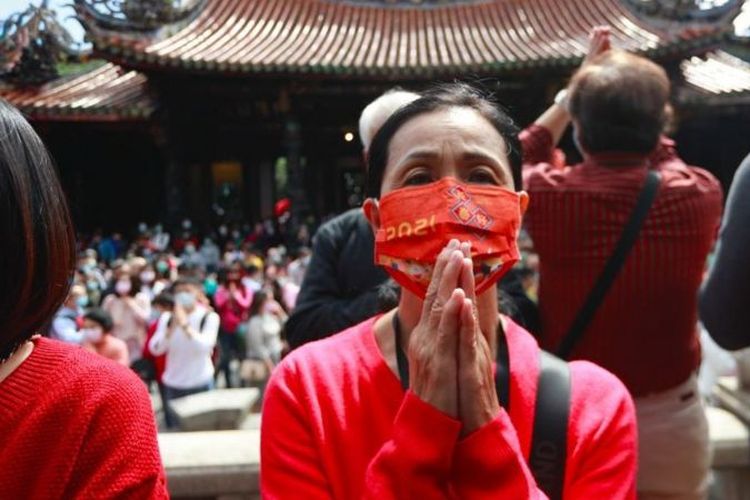 Warga Taiwan berdoa sambil memakai masker di Kuil Lungshan untuk hindari penyebaran Covid-19. [GETTY IMAGES VIA NBBC INDONESIA]