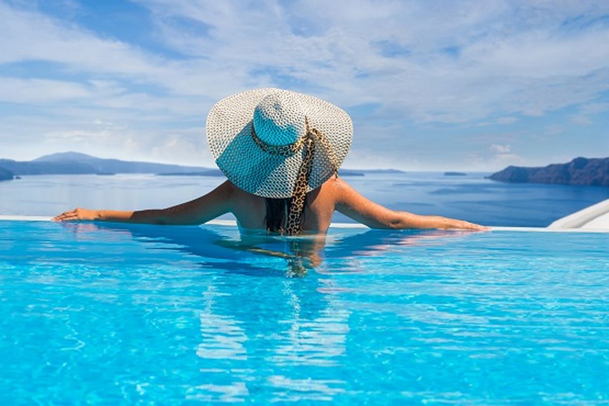 Seorang wanita sedang berenang di kolam renang di Santorini, Yunani.