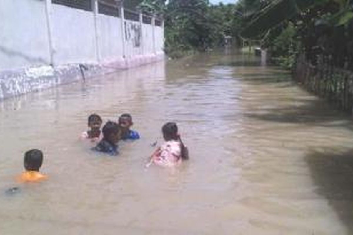 Anak-anak bermain di jalan Desa Kedungrukem, Kecamatan Benjeng, yang tergenang air luapan Kali Lamong, Rabu (28/1/2015). 

