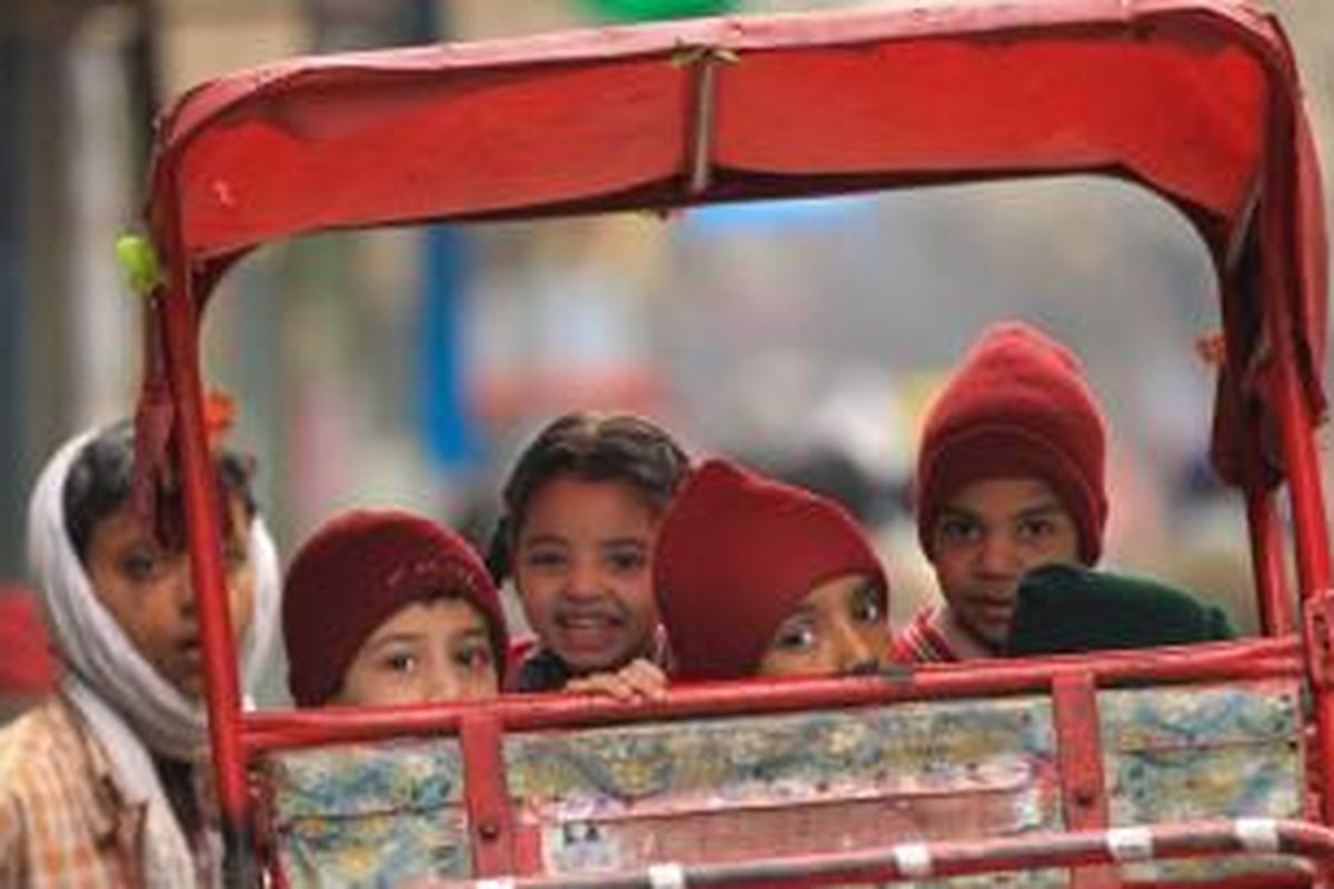 Anak-anak di kota New Delhi, India berangkat ke sekolah naik becak.