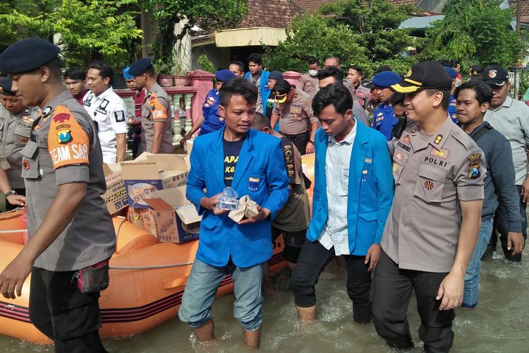 Mahasiswa bersama pihak kepolisian dan anggota TNI, saat membagikan bantuan dan sekaligus bersih-bersih sampah di Desa Iker-iker Geger, Kecamatan Cerme, Gresik, Jumat (10/1/2020).