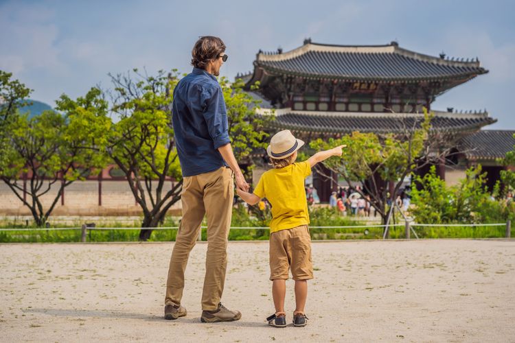 Turis ayah dan anak berwisata di depan istana di Seoul, Korea Selatan. 