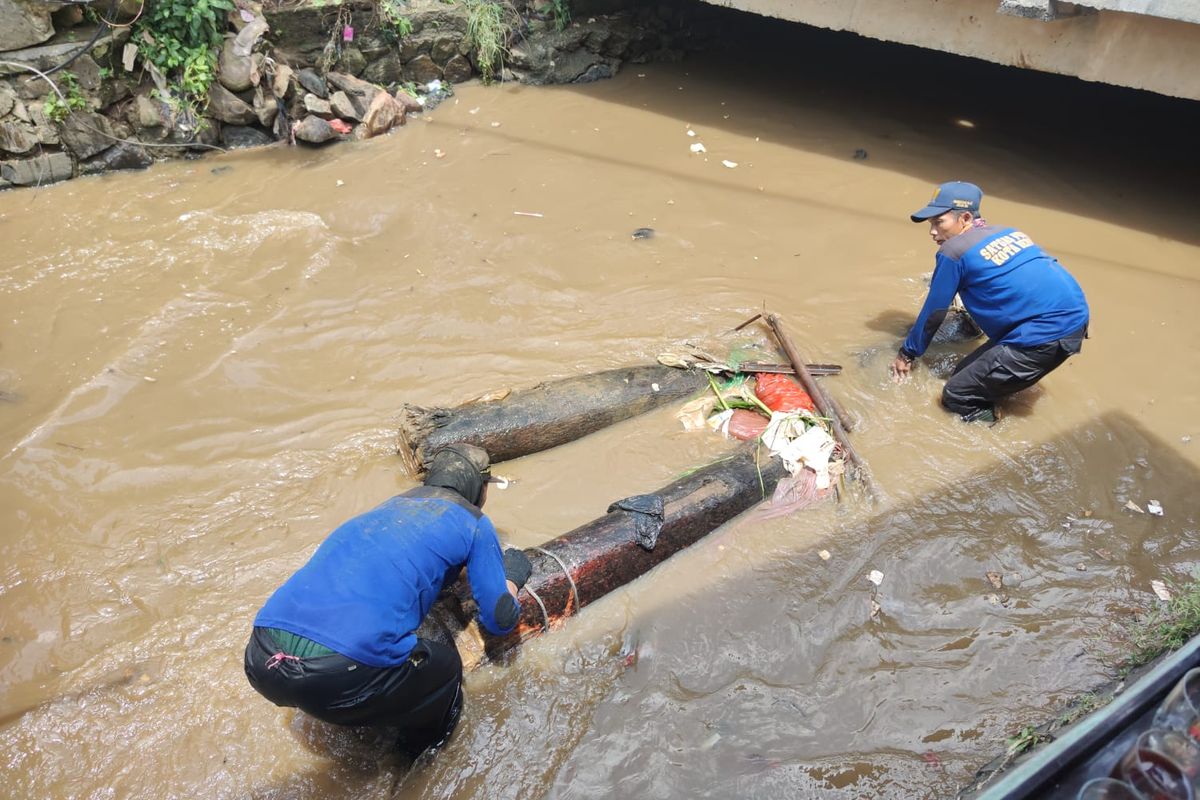 Petugas gabungan dari unsur pemadam kebakaran dan PUPR Kota Depok mengevakuasi batang pohon besar yang terbawa aliran Kali Licin yang menyebabkan banjir di Simpang Mampang, Pancoran Mas, pada Kamis (23/9/2021).