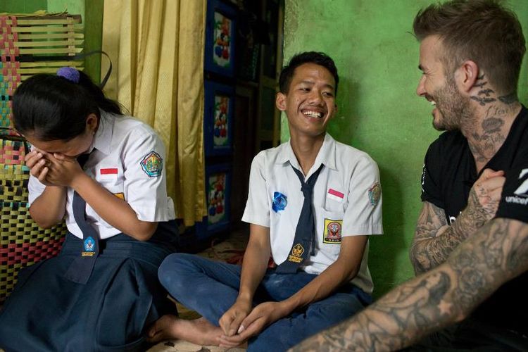 Duta Kehormatan UNICEF David Beckham tertawa bersama Sripun (15) dan temannya, Ego, di rumah nenek Ego di Semarang, Jawa Tengah, Indonesia, 27 Maret 2018. Sripun diunjuk oleh lingkungannya untuk menjadi agen perubahan dan berpartisipasi dalam program anti-bullying yang diinisiasi UNICEF.