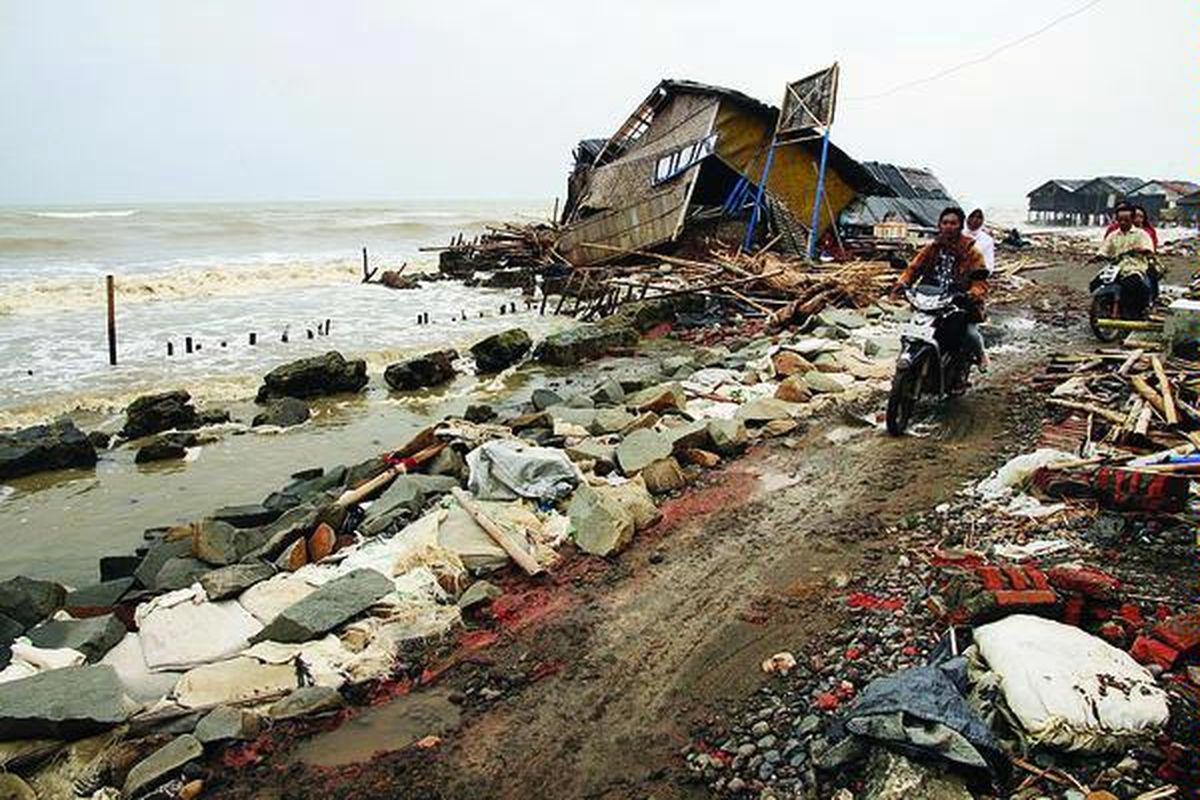 Warga melintasi rumah dan jalan desa yang rusak akibat gempuran gelombang Laut Jawa di Desa Cemarajaya, Kecamatan Cibuaya, Kabupaten Karawang, Jawa Barat, beberapa waktu lalu. Kiprah tokoh dan aktivis lingkungan di sejumlah desa terbukti mampu menjaga pohon bakau dan ekosistem mangrove sebagai benteng alami di pesisir utara.