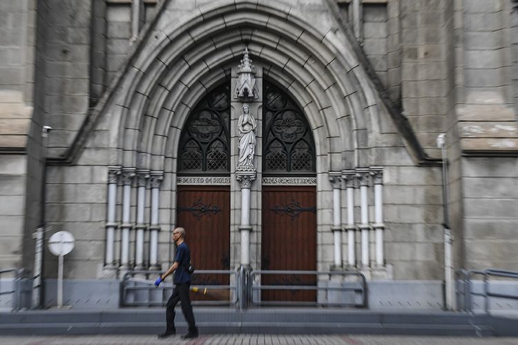 Petugas kebersihan melintas di depan pintu Gereja Katedral, Jakarta, Minggu (5/4/2020). Setelah Kemenkes resmi merilis Peraturan Menteri Kesehatan No.9 Tahun 2020 tentang Pembatasan Sosial Berskala besar (PSBB) dalam Rangka Perception Penanganan COVID-19, bentuk ibadah gereja dilakukan secara live streaming melalui media sosial, termasuk rangkaian ibadah paskah yang akan jatuh mulai Kamis (9/4/2020) hingga Minggu (12/4/2020).