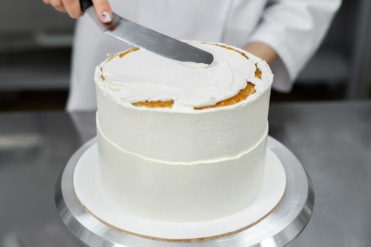 Ilustrasi melapisi kue dengan krim. 