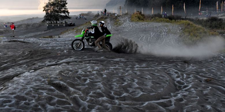 Pengunjung melintas di hamparan pasir yang diselimuti empun upas di kawasan Gunung Bromo, Probolinggo, Jawa Timur, Minggu (30/6/2019). Fenomena embun upas tersebut disebabkan penurunan suhu yang mencapai 0 derajat celcius pada malam hari. 