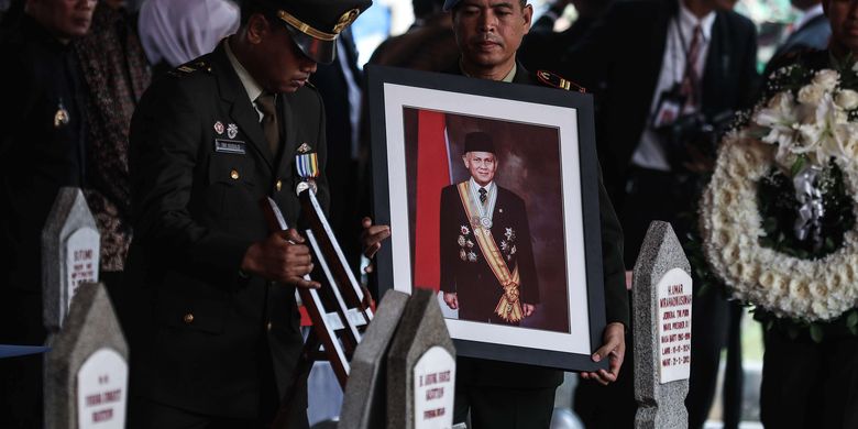 Personel Pasukan Pengamanan Presiden (Paspampres) membawa bingkai foto Presiden ke-3 Republik Indonesia, BJ Habibie menuju liang lahat saat tiba di Taman Makam Pahlawan Nasional Utama Kalibata, Jakarta Selatan, Kamis (12/9/2019). BJ Habibie meninggal dunia pada hari Rabu (11/9/2019) pukul 18.05 WIB setelah menjalani perawatan di RSPAD.