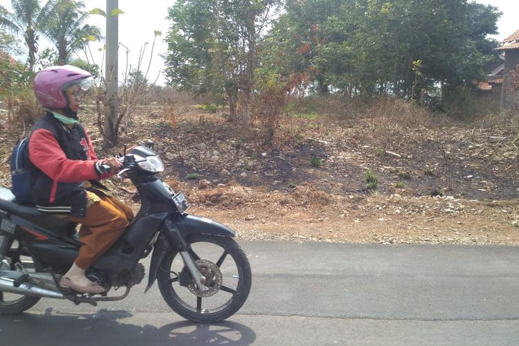 Pengendara melintas di depan lahan bekas perumahan syariah Pesona Darussalam Residence di Jalan Yogyakarta, Pekon Yogyakarta Selatan, Pringsewu, Lampung, Jumat (29/11/2019). Lahan ini kini terbengkalai dan ditumbuhi ilalang setelah pembangunan terhenti pada Desember 2015.