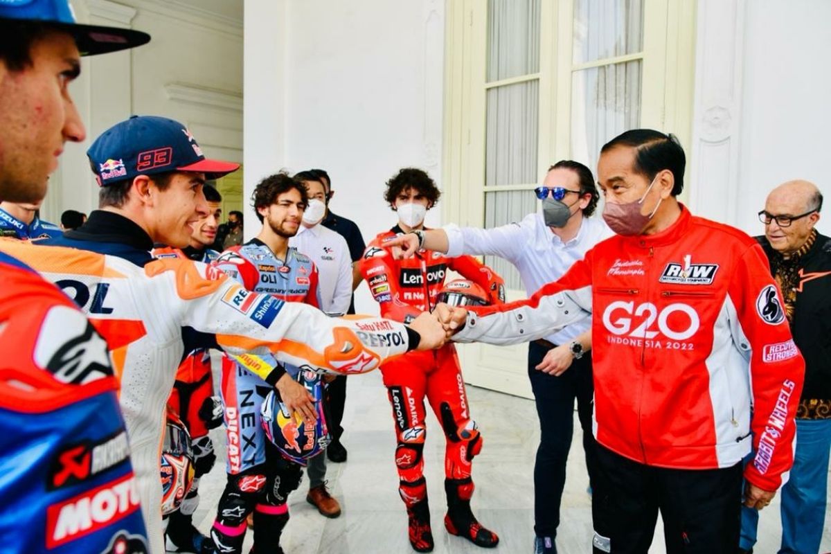 Indonesia's President Joko Widodo shares a light moment with 20 MotoGP racers before he flags off the convoy of the racers in front of Merdeka Palace in Jakarta on Wednesday, March 16, 2022. 