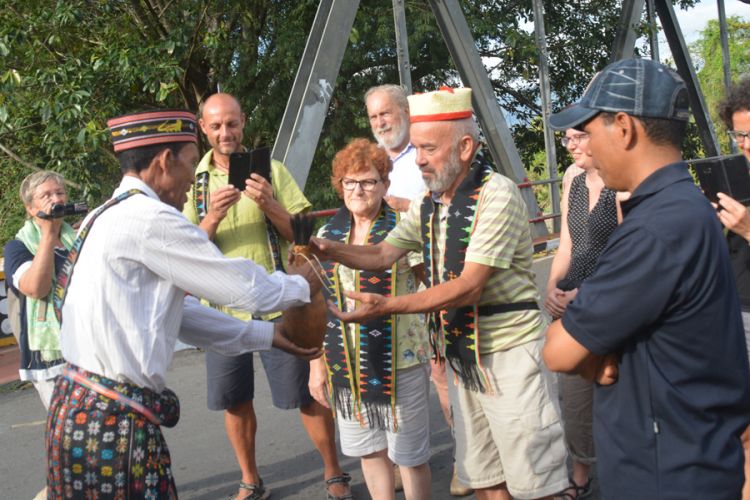 Ketua rombongan turis Italia dan Jerman menerima Moke Kepok Sundung di Jembatan Waemokel, Manggarai Timur, NTT, Rabu (15/8/2018).