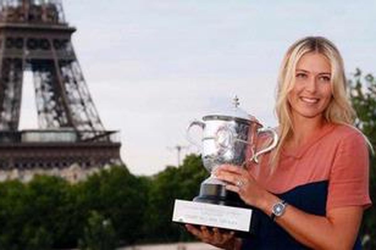 Petenis Rusia, Maria Sharapova, mencium trofi Perancis Terbuka, yang diraihnya setelah kalahkan Sara Errani di final, Sabtu (9/6/2012). Dia berpose dengan latar belakang menara Eiffel.