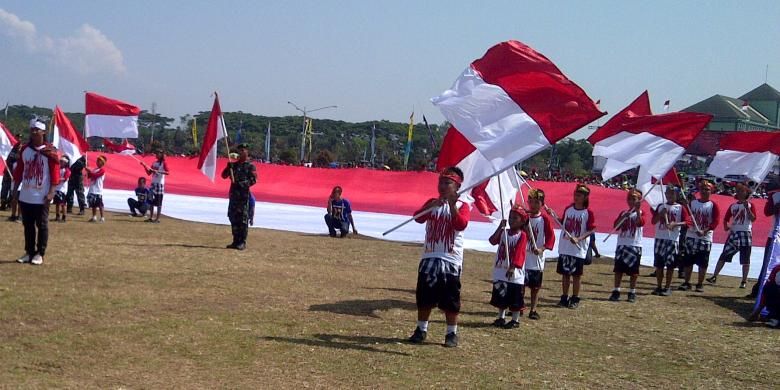 Aremania dan anggota TNI membentangkan bendera merah putih raksasa dalam upacara HUT TNI ke 68 di lapangan Rampal, Malang, Jawa Timur, Sabtu (05/10/2013).