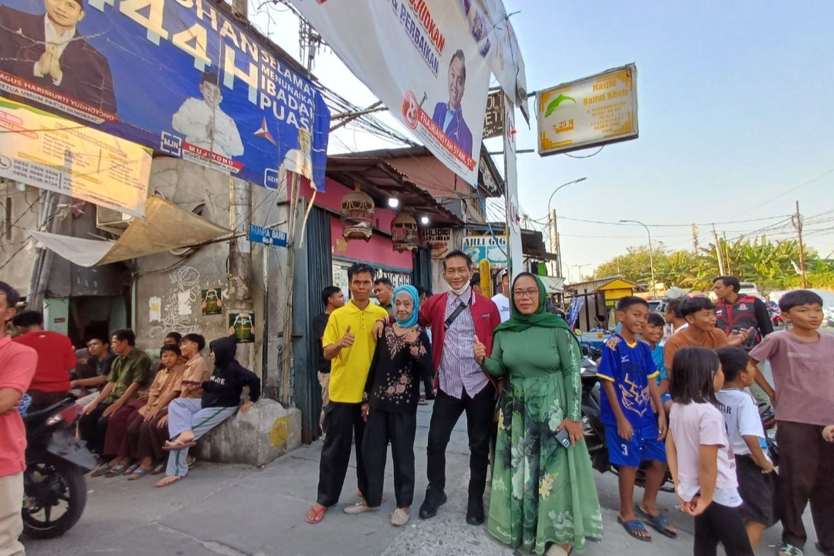 Pemilik Rumah Belajar Waduk Pluit, Nenek Dela (73) saat berswafoto bersama warga yang lain. Mereka menunggu di depan Gang VIII, Jalan Muara Baru Raya, Penjaringan, Jakarta Utara untuk kedatangan Ketua Umum Partai Solidaritas Indonesia (PSI) Kaesang Pangarep..