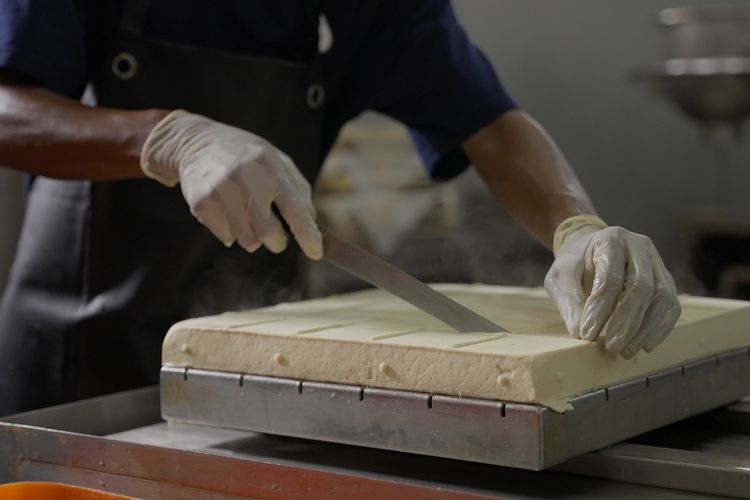 Pekerja sedang memotong tahu yang baru diproduksi di Tofu Deli, Kamis (21/3/2024).