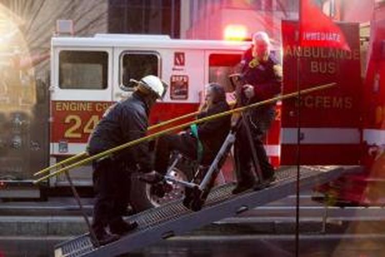 Seeorang perempuan dibawa dengan kereta dorong ke sebuah mobil ambulans saat orang-orang dievakuasi dari sebuah stasiun kereta bawah tanah yahg penuh asap di Washingtong, Senin (12/1/2015) sore.