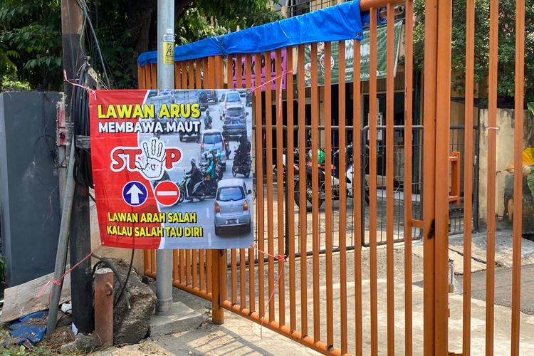 Kreator konten Laurendra Hutagalung memasang spanduk imbauan agar pengendara tak melawan arus di flyover Slipi, Palmerah, Jakarta Barat, Rabu (6/9/2023). 