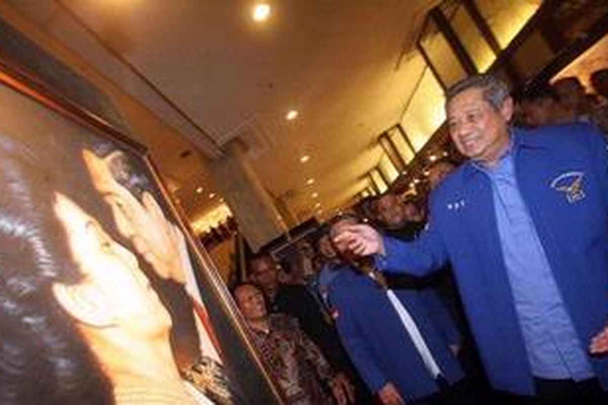 Ketua Majelis Tinggi Partai Demokrat Susilo Bambang (kanan) Yudhoyono melihat lukisan dirinya bersama Ibu Ani Yudhoyono usai memberikan keterangan pada wartawan dalam konferensi pers Rapat Pimpinan Nasional PD, di Hotel Sahid, Jakarta, Minggu (17/2/2013).