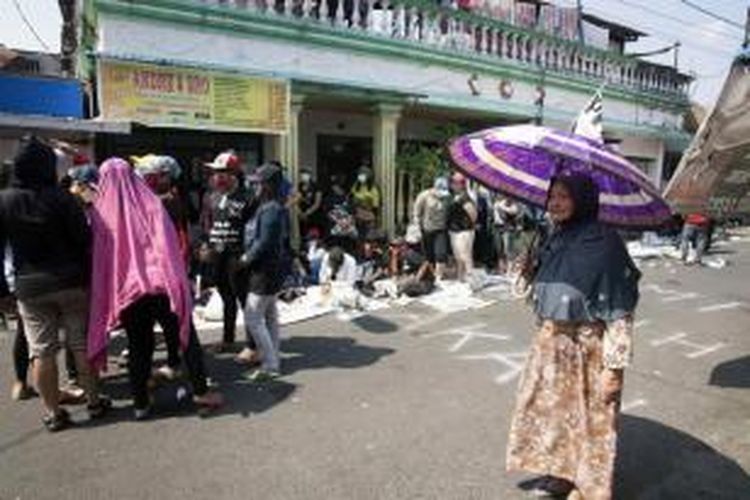 Seorang ibu melintas di dekat para pekerja seks yang berunjuk rasa menentang penutupan kawasan Dolly di Surabaya, 5 Juni 2014. Wali Kota Surabaya Tri Rismaharini telah menetapkan menutup kawasan bordil di Dolly pada 18 Juni 2014.