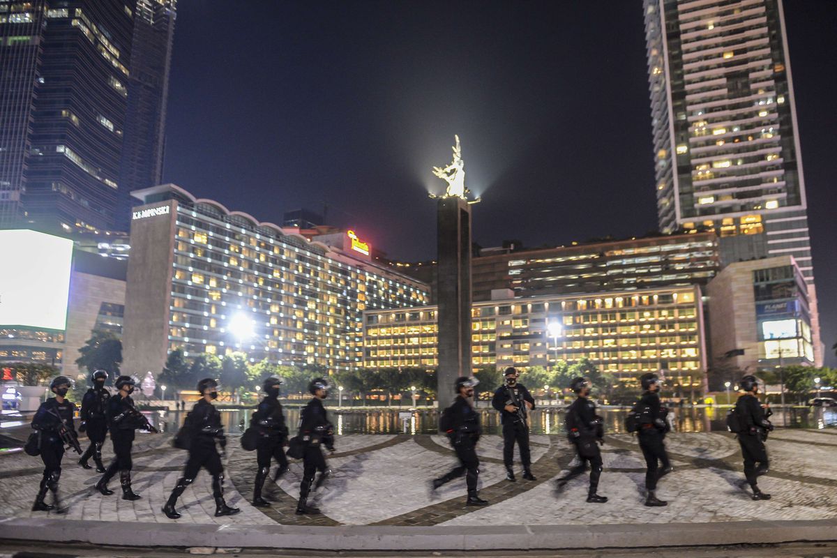 Sejumlah personel Satbrimob Polda Metro Jaya berjaga saat pemberlakuan Crowd Free Night di Bundaran Hotel Indonesia, Jakarta, Jumat (31/12/2021). Polda Metro Jaya memberlakukan pengendalian mobilitas Crowd Free Night (malam bebas keramaian) pada malam tahun baru 2022 yang berlangsung mulai pukul 22.00 - 04.00 WIB.