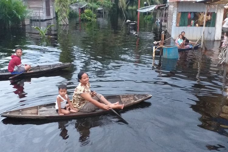 Sejumlah warga korban banjir beraktivitas menggunakan perahu di Desa Bonai, Kecamatan Bonai Darussalam, Kabupaten, Riau, Selasa (3/12/2019).