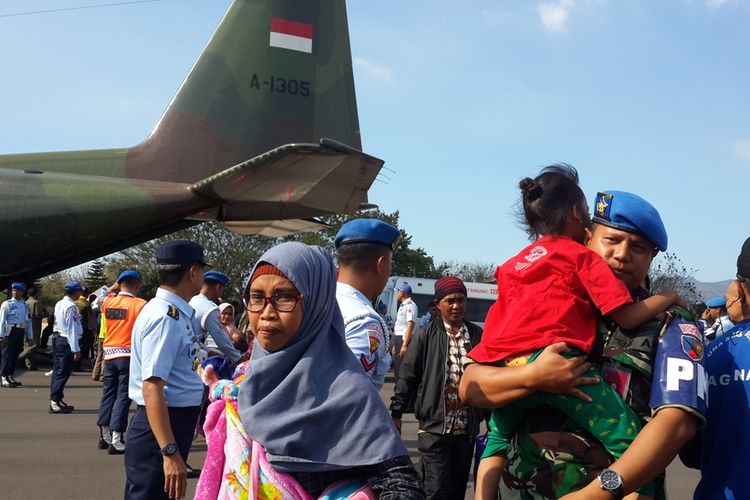 Salah satu prajurit TNI saat membantu warga Jawa Timur yang dipulangkan dari Wamena, Papua dengan menggendong anaknya di Lanud Abdulrachman Saleh, Kabupaten Malang, Rabu (2/10/2019)