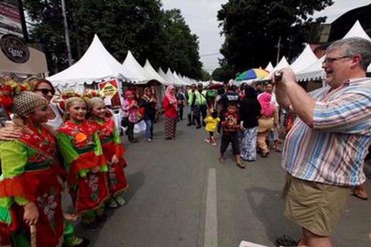 Pekerja ekspatriat berfoto dengan penari lenggang nyai di acara Festival Palang Pintu di Jalan Kemang, Jakarta, Sabtu (8/6/2013). Festival budaya dan kuliner Betawi tersebut telah diselenggarakan kedelapan kalinya dalam rangka HUT ke-486 DKI Jakarta dan akan berlangsung 8-9 Juni 2013. KOMPAS/LUCKY PRANSISKA