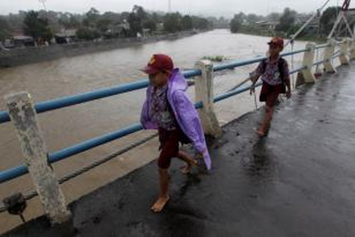 Warga melintas Bendungan Katulampa, Bogor, Jawa Barat, saat hujan lebat mengguyur Bogor, Rabu (9/1/2013). Ketinggian air di Bendungan Katulampa mencapai 120 sentimeter melebihi batas normal yaitu 50 sentimeter sehingga ditetapkan status siaga tiga. Warga terutama yang tinggal di daerah bantaran-bantaran sungai dihimbau bersiaga dan mengantisipasi datangnya banjir. KOMPAS IMAGES/KRISTIANTO PURNOMO