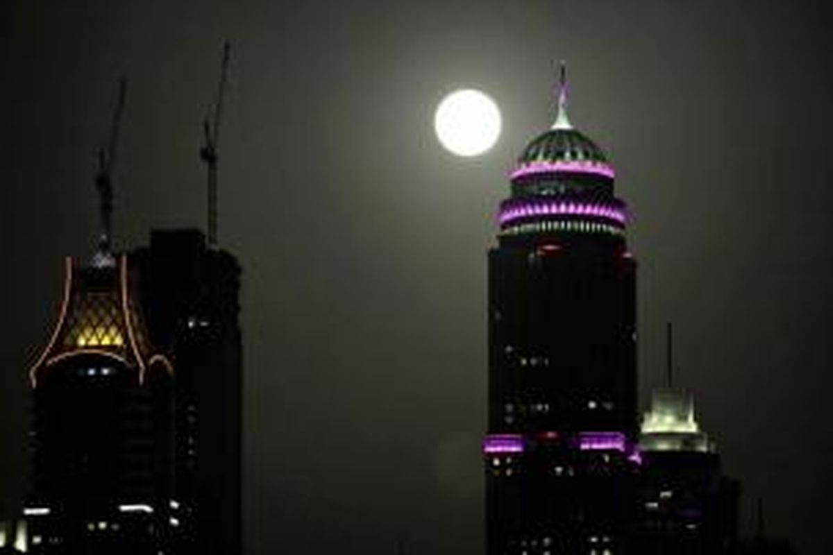 Bulan purnama terlihat di belakang bangunan hunian tertinggi di dunia, menara Princess di Dubai, Uni Emirat Arab, 23 Juni 2013. Bulan yang akan mencapai tahap penuh pada Minggu, 13.5 persen lebih dekat ke bumi dan dikenal sebagai fenomena supermoon.